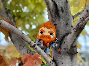 橙色頭髮和鬍子的Funko Pop公仔棲息在樹枝上，伴有秋葉。 — 迪士尼反派 壁紙