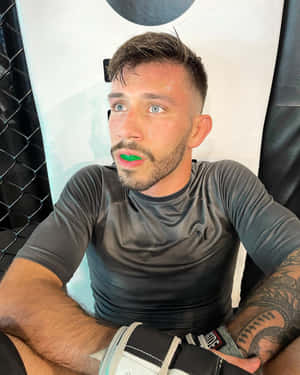嘴上塗著綠色顏料的運動員在訓練後於MMA籠中休息。 — 終極格鬥冠軍賽 壁紙