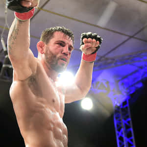 一位勝利的MMA鬥士在競技場燈光下高舉拳頭慶祝。 — 運動 壁紙