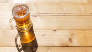 一個玻璃啤酒杯帶泡沫放在木桌上，在明亮陽光下。 — 啤酒 壁紙