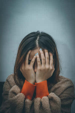 人用手遮臉，身穿棕色刷毛和橙色毛衣。 — 生氣 壁紙