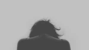 深色頭髮的人將頭低下朝向純灰色背景。 — 悲傷女孩 壁紙