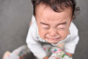 一個閉著眼睛、嘴角下垂哭泣的嬰兒。 — 小莫娜 壁紙