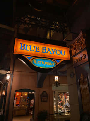 Blue Bayou Restaurant 標誌在夜間與華麗建築一起發光。 — 3:4 壁紙