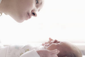 母親在柔和自然光線中溫柔地看著她的新生嬰兒。 — 白色美學動圖 壁紙