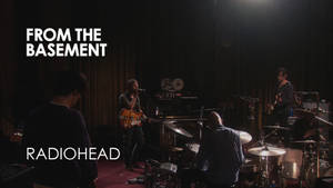 Radiohead 在黑暗的地下場地中進行現場表演，配有舞台燈光。 — 音樂 壁紙
