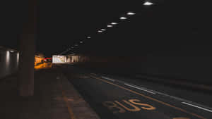 夜晚空無一人的城市隧道，帶有公車站標記和頭頂燈光。 — 暗黑地牢 壁紙