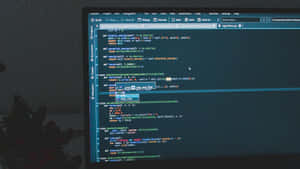 一個人的剪影坐在書桌前，電腦螢幕顯示 Python 程式碼。 — 雙螢幕 壁紙