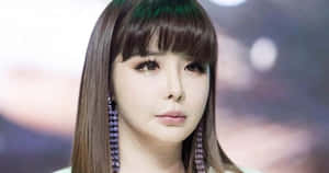 長棕髮和紫色珠耳環的女性向前看。 — 2NE1 壁紙