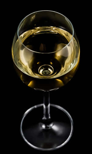 一個裝有金色液體的酒杯，置於黑色背景上。 — 乾淨 壁紙