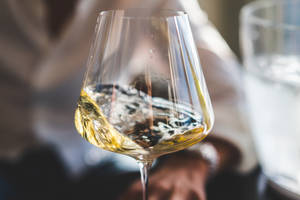 一隻手在玻璃杯中旋轉白酒，氣泡上升。 — 葡萄酒 壁紙