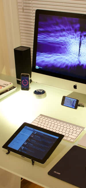 科技工作站，配有iMac、平板電腦和揚聲器，在明亮的桌面上 — iPhone 15 Pro 壁紙