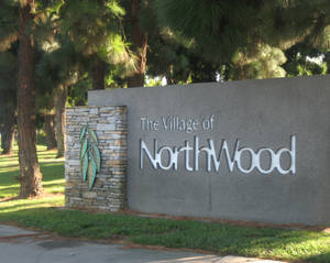 一個為 The Village of NorthWood 而設的石製標誌，位於長滿青草、有松樹的公園內。 — 草地 壁紙