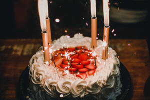 生日蛋糕配草莓和閃爍蠟燭，在昏暗燈光下發光。 — 蛋糕 壁紙