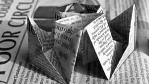 一個摺疊的報紙算命器放在報紙表面上。 — Old Paper 壁紙