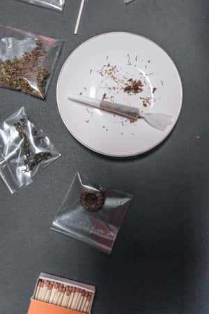 用過的大麻煙捲在盤子上，有香草袋和火柴在深色表面。 — 小米平板 9 Pro 壁紙
