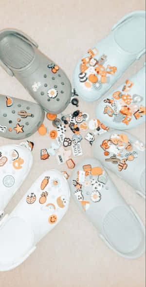 柔和粉彩Crocs飾以秋季吊飾，在米色地板上排列成圓形。 — Pixel Fold 壁紙