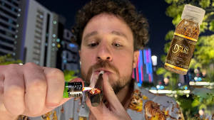 男人在夜晚的城市中點燃大麻煙，有霓虹燈和一個漂浮的香料瓶。 — 抽菸 壁紙