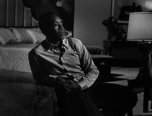 一個男人獨自坐在昏暗的臥室裡，在燈光下顯得若有所思。 — 豪斯医生 壁紙