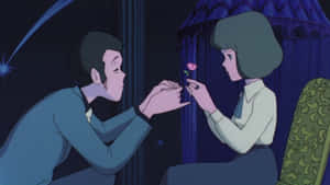 男人跪著向坐在昏暗房間裡的女士獻上一朵粉紅玫瑰，夜晚時分。 — 魯邦三世 壁紙