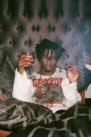 留著辮子頭的男人在皮革沙發上拿著酒杯和香煙。 — Die Lit 壁紙