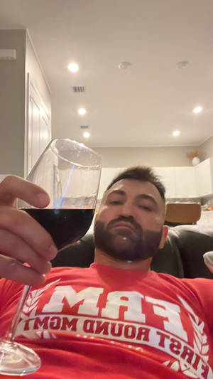 穿紅色襯衫的男人在室內拿著一杯紅酒放鬆。 — 終極格鬥冠軍賽 壁紙