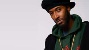 穿著綠色連帽衫和黑色貝雷帽、戴珠鏈的男人看著相機。 — 金錢 壁紙