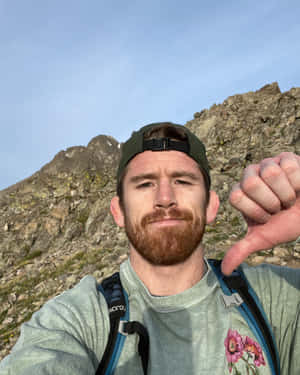 男人在山中徒步旅行做出拇指向下手勢 — 山景 壁紙