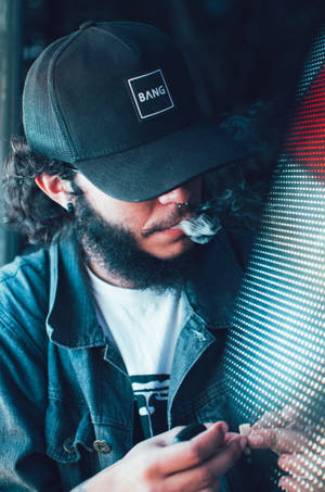 留鬍鬚戴帽的男人在夜間於發光LED牆附近呼出煙霧。 — 抽菸 壁紙