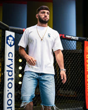 MMA拳手身穿白色T恤和破洞牛仔褲，身處八角籠內。 — 運動 壁紙