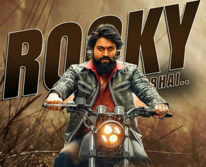 留鬍鬚的男人在摩托車上，下方有粗體字 Rocky Bhai