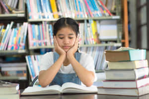 疲倦的女孩在圖書館學習時雙手托頭休息。 — 讀書 壁紙