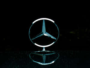 發光 Mercedes-Benz 標誌在深色表面上的倒影。 — Mercedes-Benz 壁紙