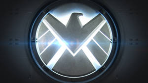 S.H.I.E.L.D.標誌在黑暗金屬房間內的圓形觀察窗中發光。 — 漫威 壁紙