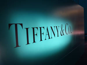 Tiffany & Co.標誌在深色牆壁上發出綠松石色光芒。 — 蒂芙尼藍 壁紙