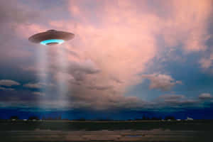 一個發光的UFO盤旋在田野上空，在黃昏時投射出光束。 — 太空船 壁紙
