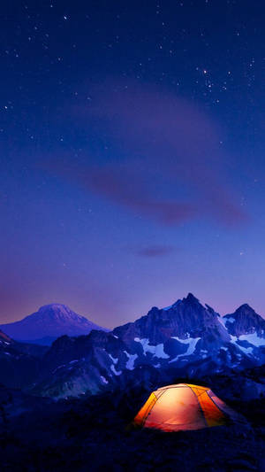 一個發光的帳篷，在積雪的山脈中，上方是星空暮色天空。 — 山景 壁紙