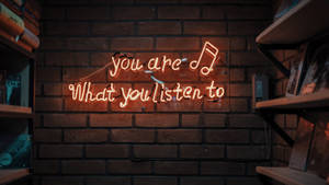 磚牆上寫著「you are what you listen to」的霓虹燈牌與書架