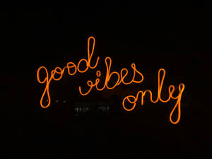 夜間發出橙色光芒、寫有 good vibes only 的霓虹燈牌。 — 霓虹橘 壁紙