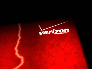 Verizon標誌在帶有裂縫的紅色紋理表面上以白色照明。 — 威訊 壁紙
