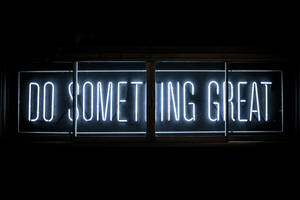 一個明亮的霓虹燈牌，上面寫著「Do Something Great」，背景為黑暗。 — 激勵 壁紙