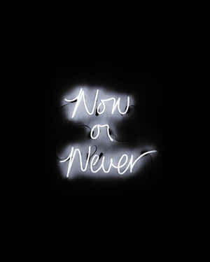 一個發光的霓虹燈牌，上面寫著「Now or Never」，在黑暗的房間裡。 — Off white 標誌 壁紙