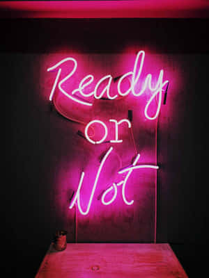 深色牆壁上、木桌上方，一個寫著「Ready or Not」的粉紅色霓虹燈牌。 — 粉紅色美學桌面 壁紙