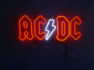 ACDC樂隊標誌霓虹燈，閃電以紅白色發光。 — 霓虹橘 壁紙