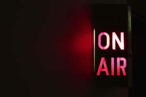 一個紅色霓虹燈「ON AIR」標誌在黑暗的工作室中發光。 — 電視 壁紙