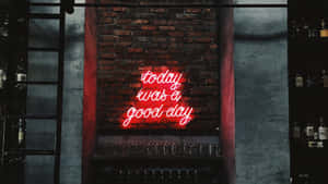 在昏暗的酒吧中，磚牆上有一個紅色霓虹燈牌，寫著「today was a good day」。 — 霓虹紅 壁紙