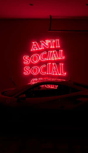 黑暗房間中汽車上方寫著 anti social social 的紅色霓虹燈牌。 — 霓虹燈 壁紙