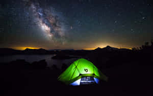 一個發光的綠色帳篷，在星空下，銀河在湖泊上方可見。 — 美麗的秋天 壁紙