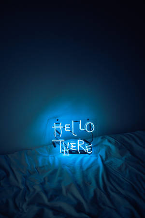 一個藍色霓虹燈牌，上面寫著 hello there，放在黑暗房間內的床上。 — 藍色美學電腦 壁紙
