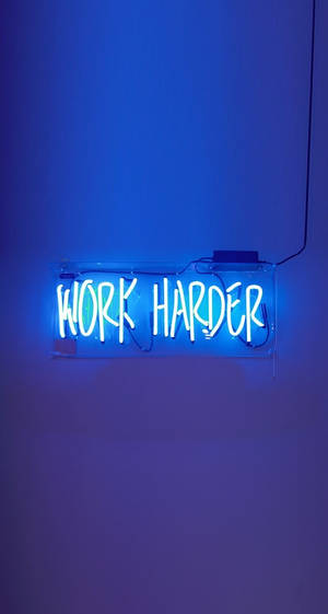 素牆上帶有 work harder 字樣的藍色霓虹燈牌。 — 動力 壁紙
